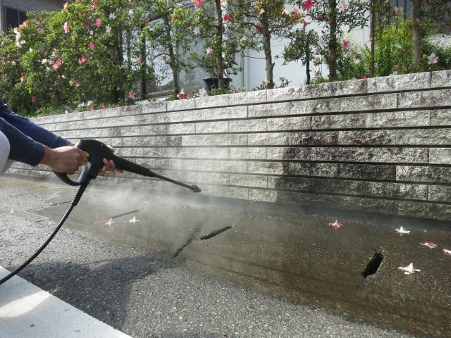 壁の汚れを高圧洗浄で落とす人